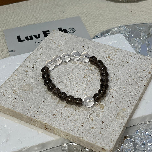 Detailed front view of the Balanced Aura Bracelet from LuvEcho Jewelry, featuring 6mm Smoky Quartz beads and a striking combination of one 8mm Crystal Quartz bead on one side and five on the other.