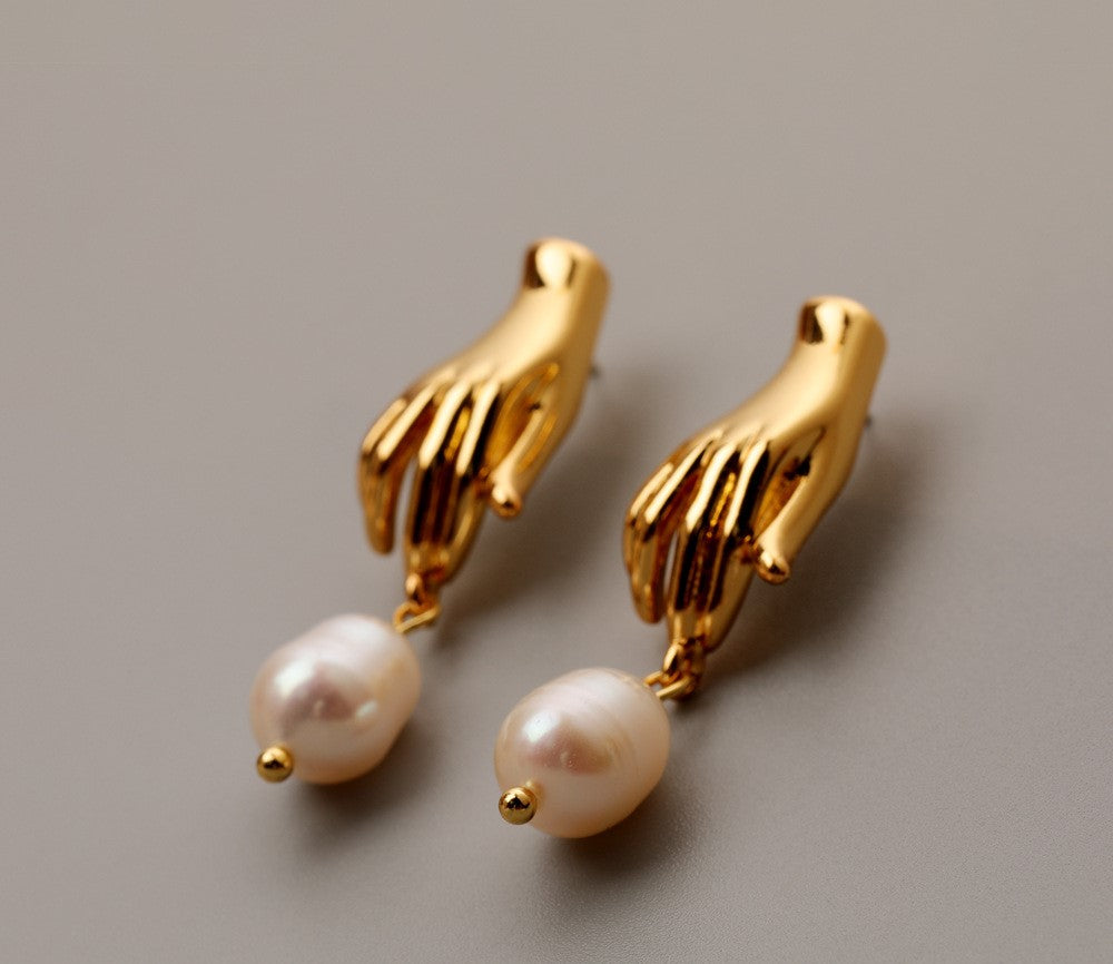 Luv Echo Jewelry - Hadley small hand baroque pearl stud earrings in gold color, featuring a hand-shaped design with a single baroque pearl in the center.